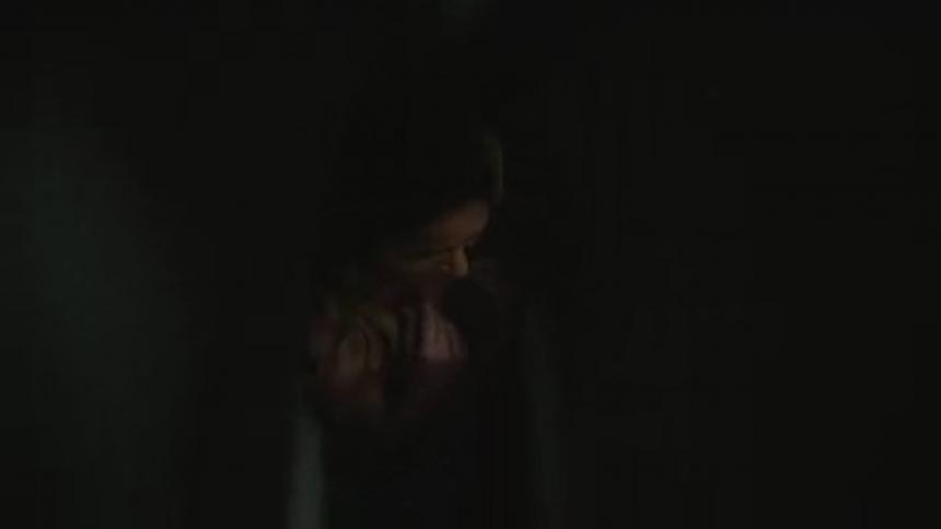 A woman closed in a tight dark space turns around