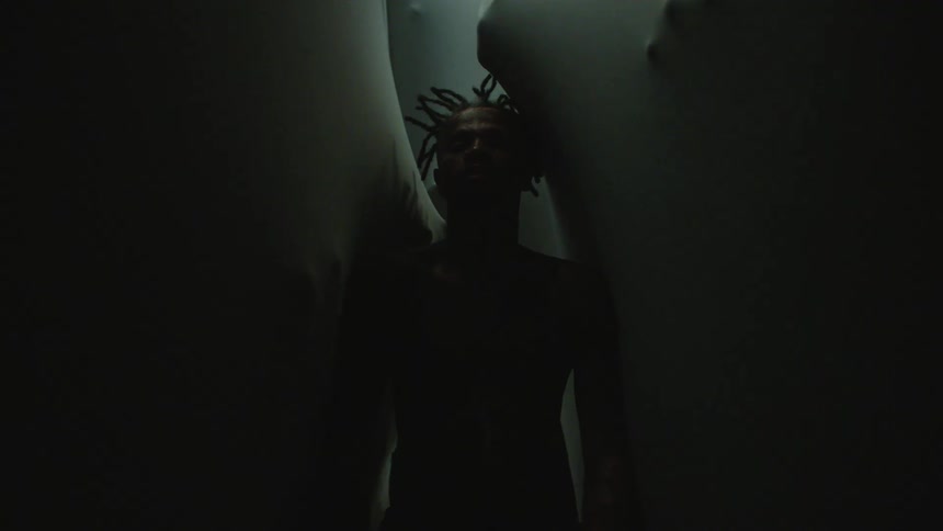 A man in a narrow space falls backwards as hands on the other side reach and grab at him