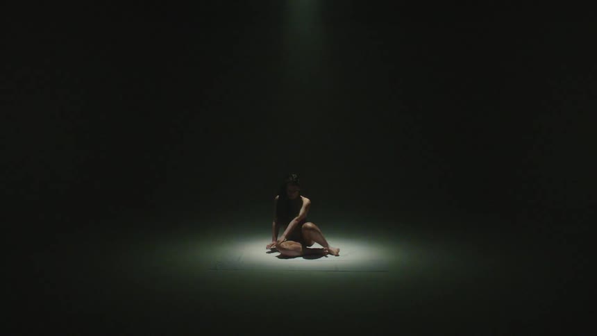 A spotlight shining on a woman who slowly stands and the light grows and glares