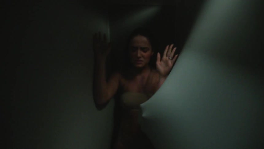 A woman fights off people trying to grab her through stretchy curtains