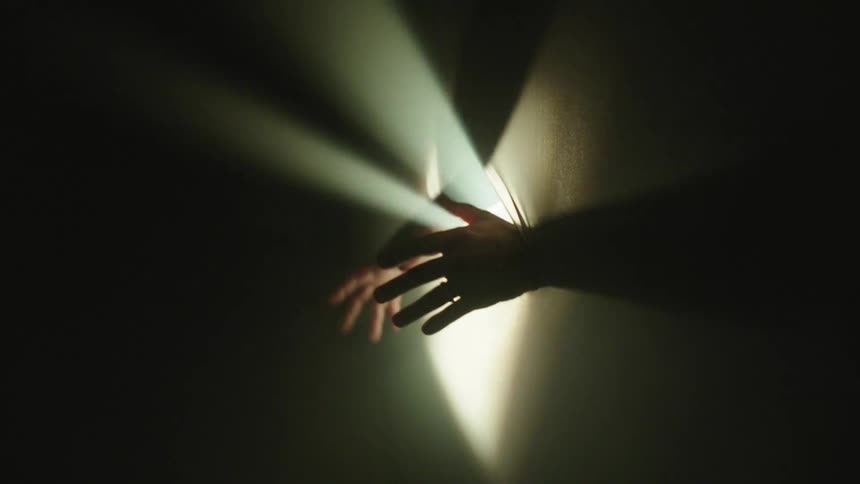 A woman reaches out through a hole from behind stretchy fabric