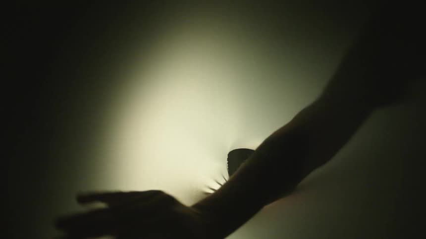A hand reaches through a hole in fabric casting a creepy shadow and image
