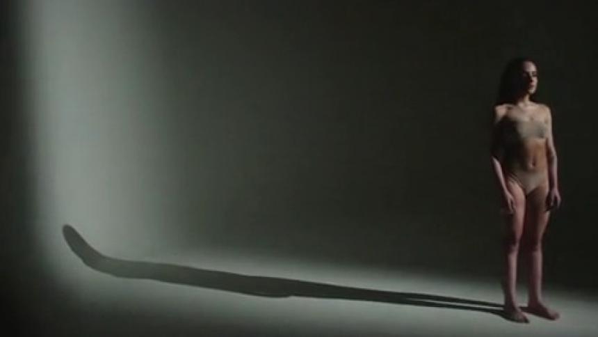 Woman standing in a swimsuit during photoshoot with shadow behind her