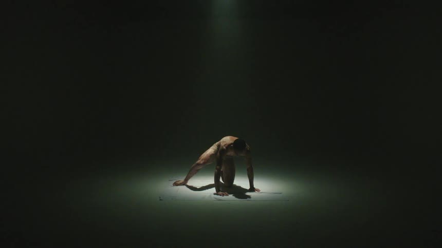 A person is alone on the floor in an abandoned room then rises into the light