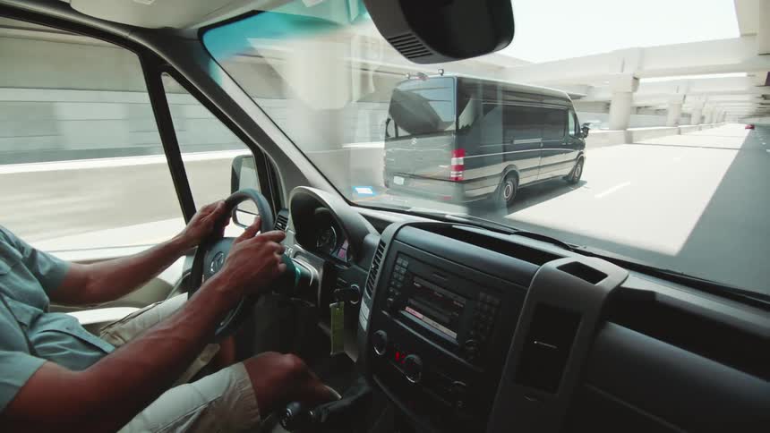 A van driver smiles as another passes him as they both travel on a sunny highway