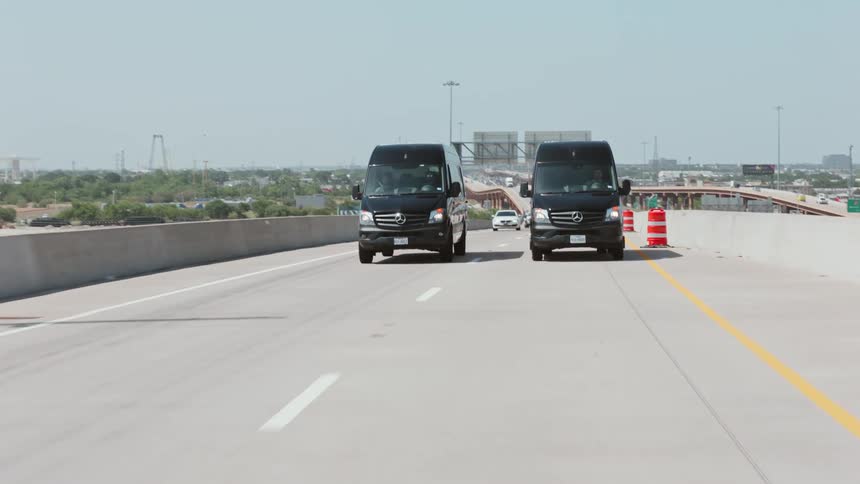Two black vans travel on the highway