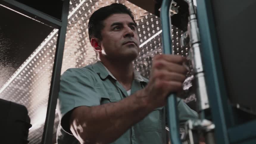 Focused male worker unloading a cart from a black transport van parked on a city street