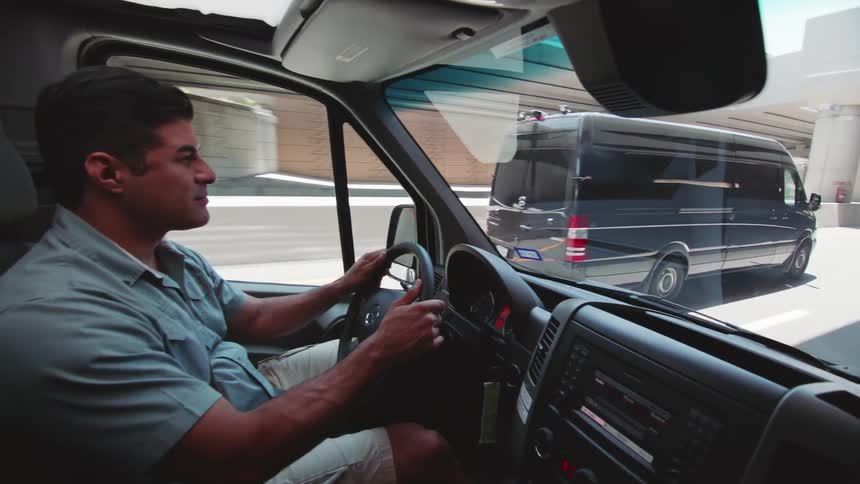 A man drives a large van on the city highway
