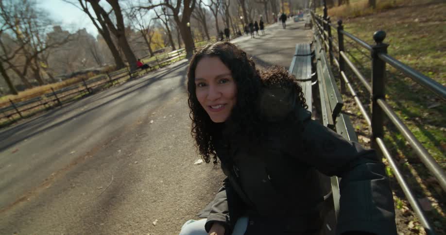 Point of view footage of a smiling happy woman sitting on a bench at a park holding hands with her partner