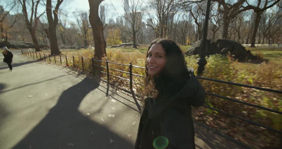 A woman is looking back as she talks and walks through a park