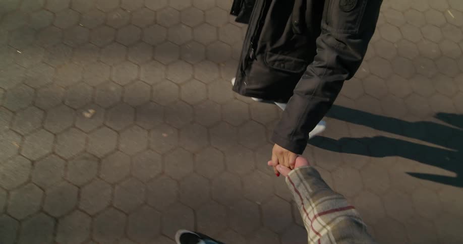 A man caresses his girlfriends hand with his thumb as they walk hand in hand