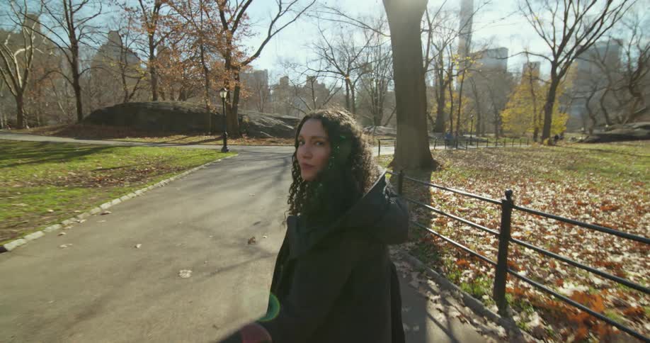 A woman looks back over her shoulder as she walks on a path in a park