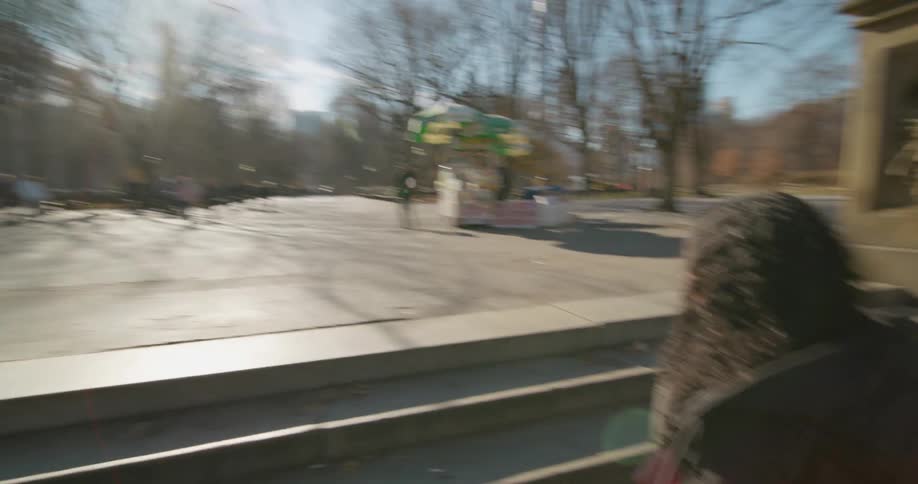A woman holds a mans hand as she walks up steps to a park where food vendors and people are on a wide pathway
