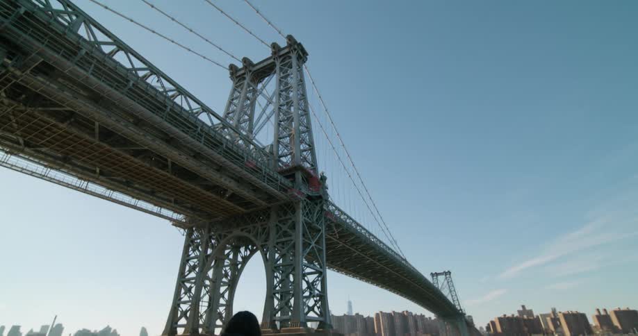 A woman stands on a dock and looks across the water at the city skyline and then turns her head back and smiles
