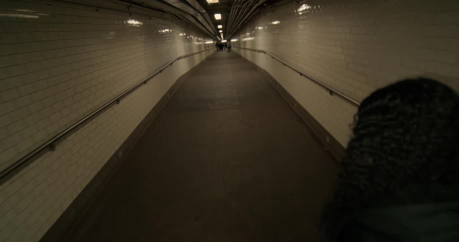 A man and woman walk hand in hand down a large corridor