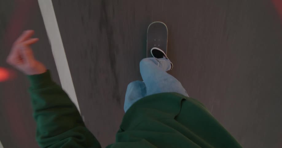 A person in a green hoodie skateboarding on a paved road