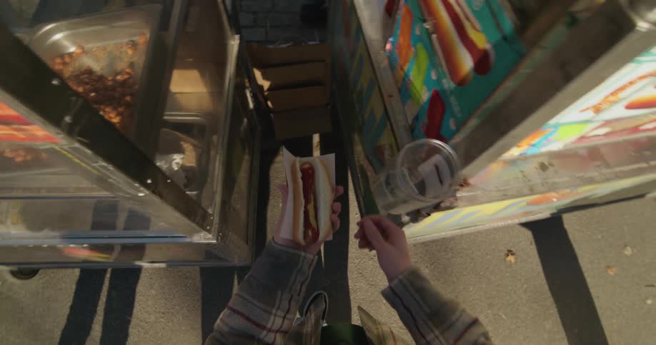 A man buying hot dogs from a street cart