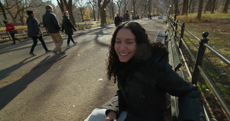 A woman is talking while sitting on the park bench