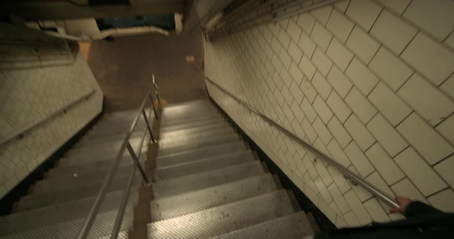 A woman walks down the stairs into the subway