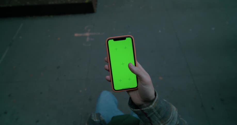 A person is using their cell phone on the sidewalk