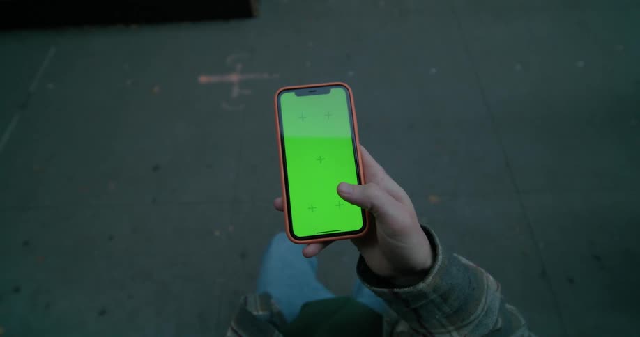 A man is standing and using his cellphone as a woman walks by