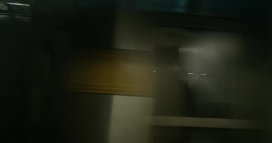 A subway train driving by a graffitied wall in a city