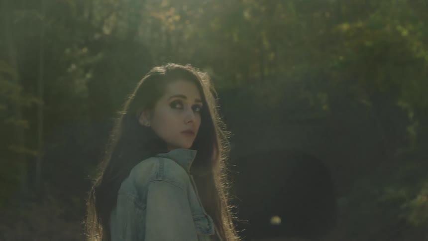 Woman looking over her shoulder in the woods on a sunny day