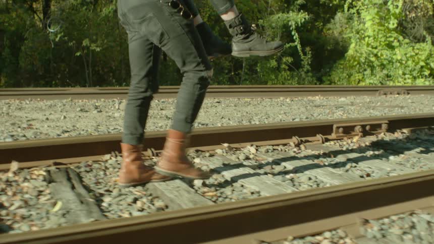 A person is carrying another person down some train tracks