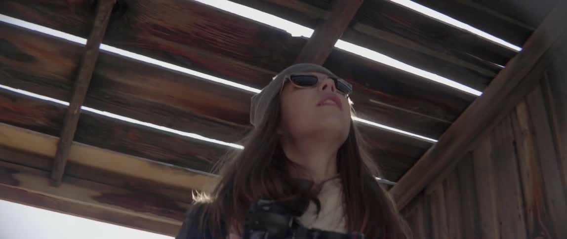 Woman Holding a Camera Looking Up at a Wooden Roof With Curious Playful Wonder.