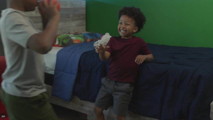 Two boys are in a bedroom laughing and playing