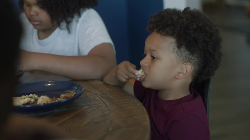 A family is seated at a table eating chicken