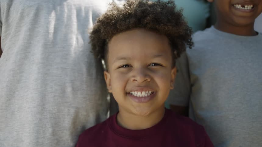 Black boy standing next to his family and smiling