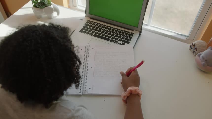 A girl is writing in her notebook at the desk