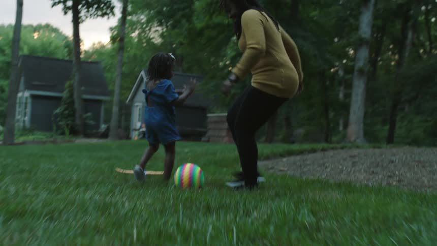 Mother and daughter play soccer in backyard