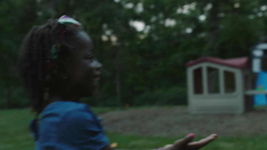 A young girl plays ball in a back yard space