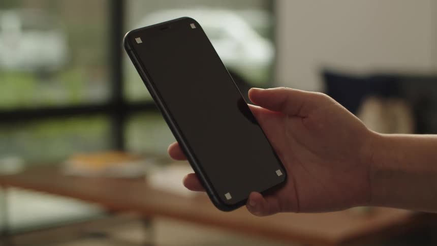 Man holding a smartphone with a black replaceable screen in his hand in front of the camera