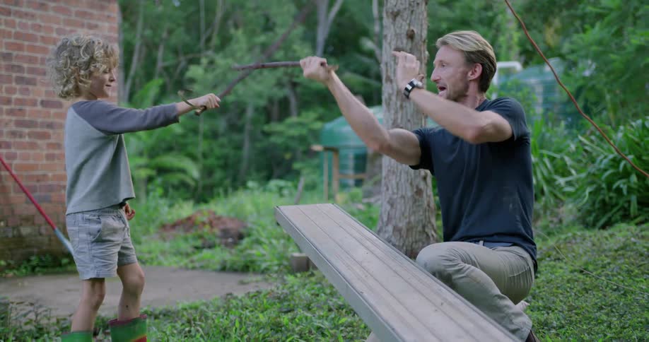 Father and son play sword fight using sticks