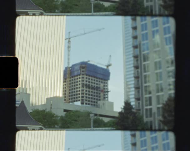 Construction cranes over a building in the city skyline caught on vintage film