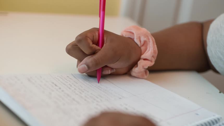 A girl is sitting at a desk writing in a notebook