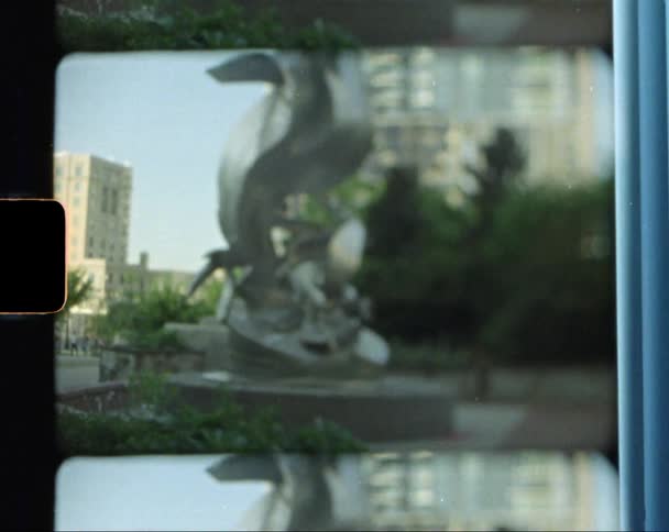 A sculpture and fountain sit in front of a tall skyscraper