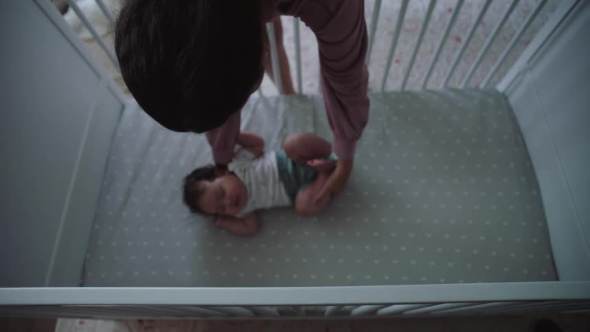 A mother lays her child to rest in the crib