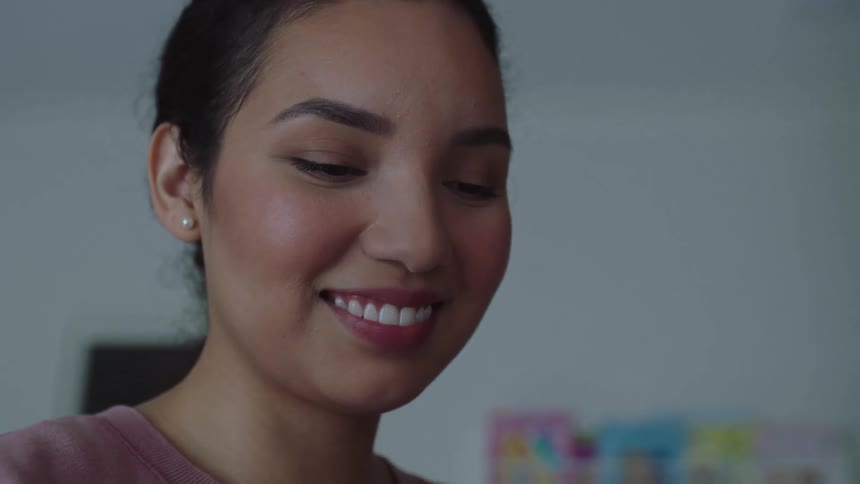 Close up of the face of a young happy woman smiling inside a room