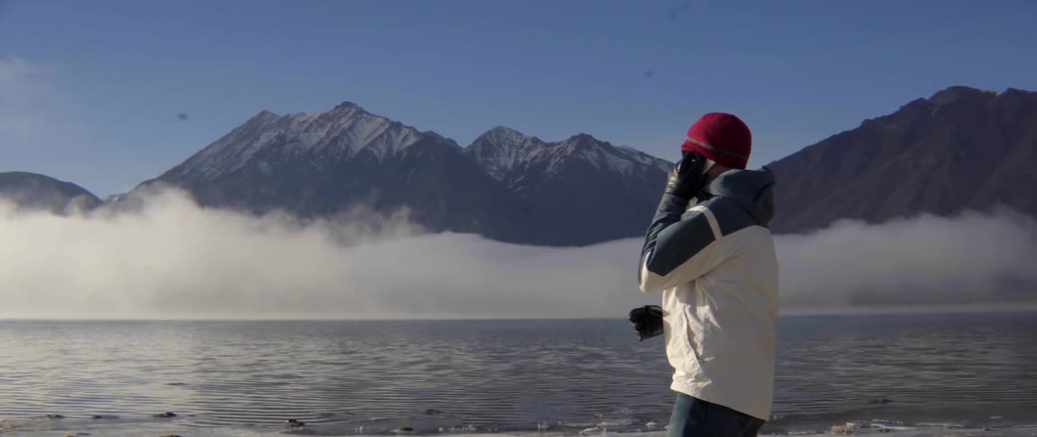 Man Using His Phone by a Mountain Range Taking in the Quiet Scenic Moment.