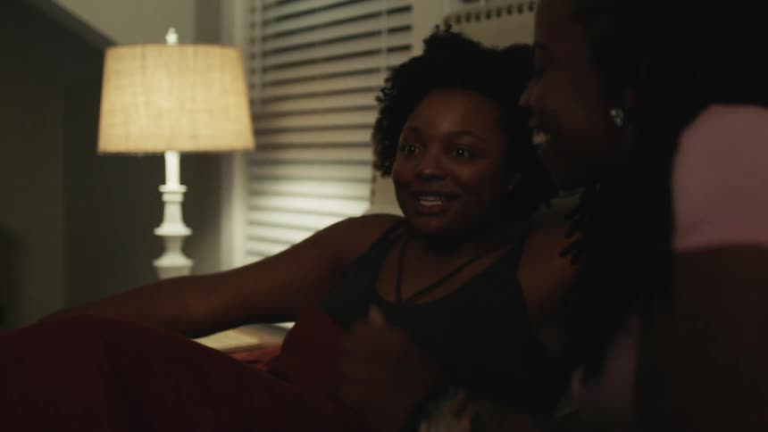 Two women lay on the bed together talking