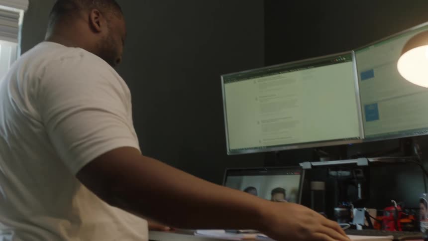 A man stands in front of a desk filled with computer screens
