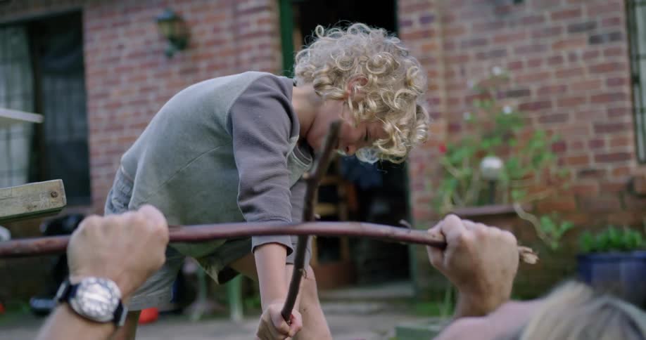 A father and son play with sticks in the yard