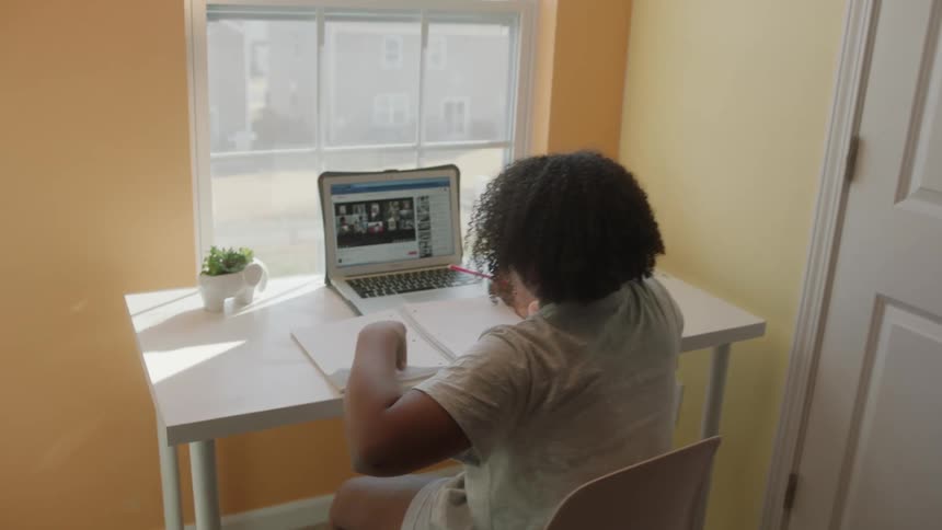 A teenage girl doing schoolwork over a video call at home