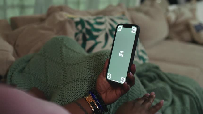 A person holds their phone on the couch