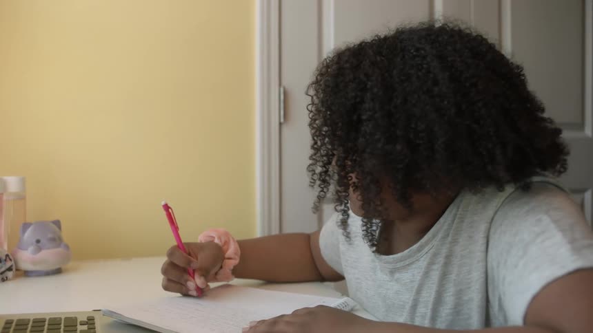 Female student nods and makes notes as she takes online classes
