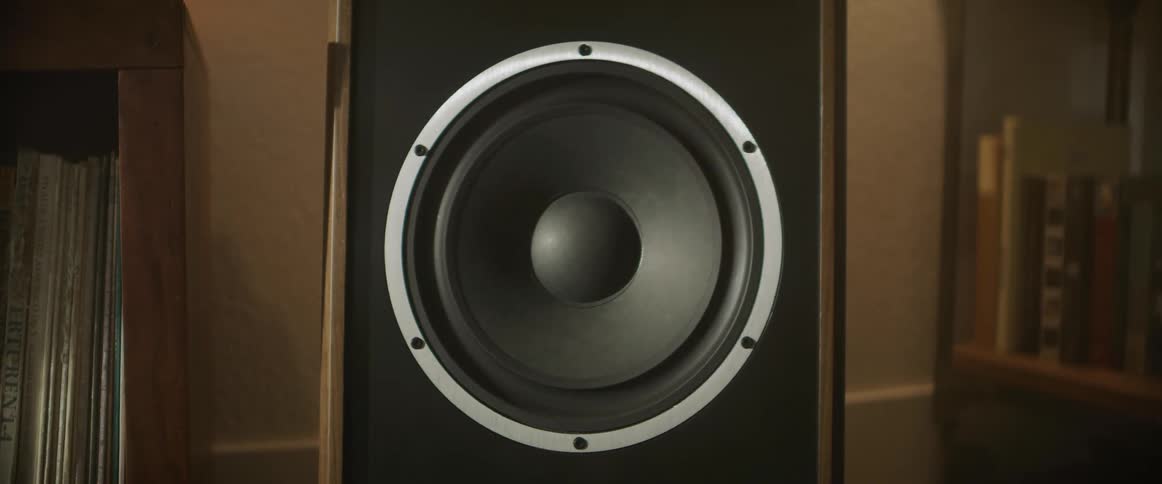 The diaphragm of a large speaker vibrates as it plays sound indoors